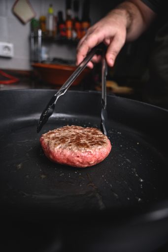 A closeup shot of a homemade hamburger cutlet frying in a pan