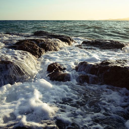 A beautiful view of splashing sea waves and rock formations in the sea at sunset