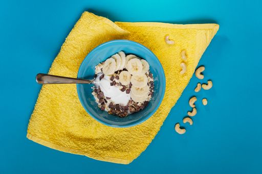 A top view of a bowl of cereal and a yellow towel on a blue background