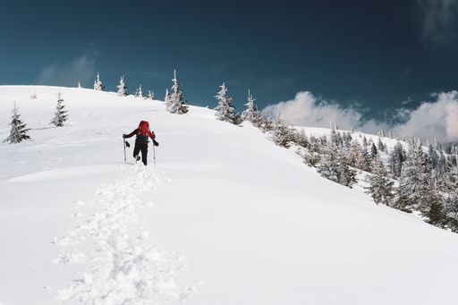 A low angle shot of a male climbing a mountain during winter