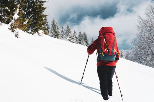 A beautiful shot of a male's back while hiking on a slope during winter