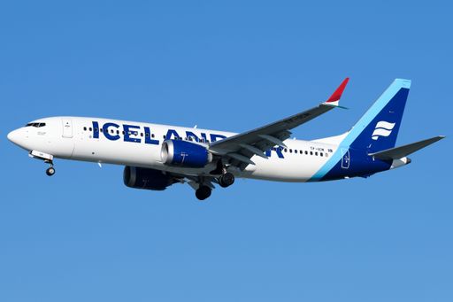 An Icelandair airplane is shown in mid-flight against a backdrop of blue sky on a clear day
