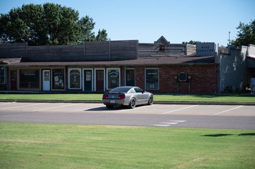 This striking image features a silver car parked on a lot near a business building