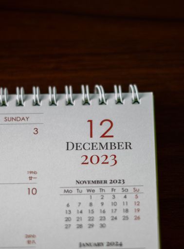 A portrait shot of a table with a calendar page open to the date December 12th, 2023