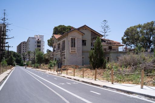 This image shows a street with a few buildings and trees on both sides