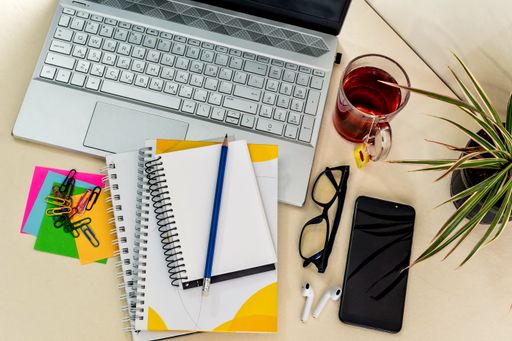 An overhead shot of an office desk with notebook with small note pads, laptop and office supplies. Business background concept