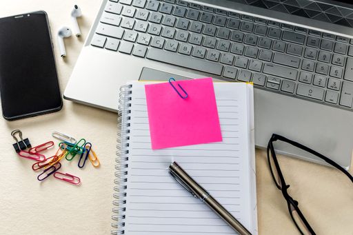A closeup of a table with notebook, note pads, laptop and office supplies. Online learning concept