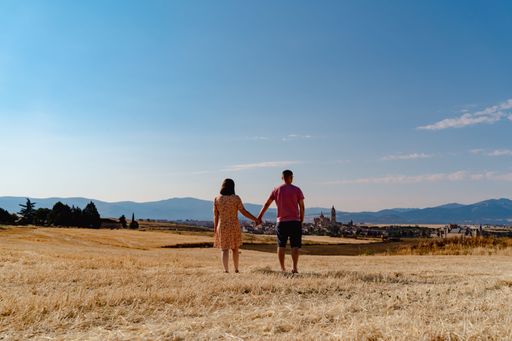 A lovely couple holding hands walking through a yellow dry meadow in Spain