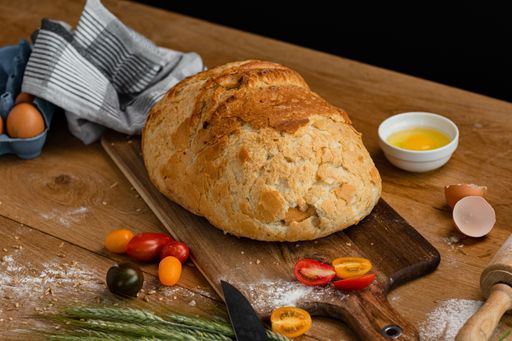 A crusty loaf of white bread on a wooden cutting board