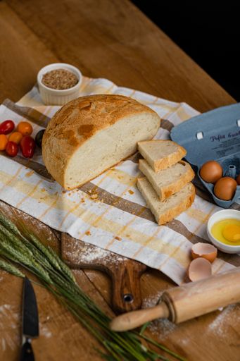 Fresh gold rustic crusty loaves of bread on a tablecloth with tomatoes and other ingredients