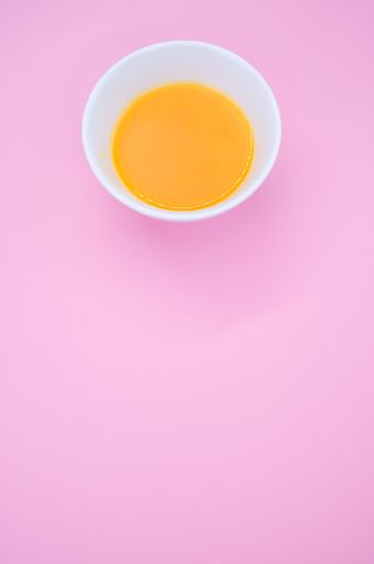 A vertical shot of a paint wash bowl with yellow-stained water on a pink background and space for your text