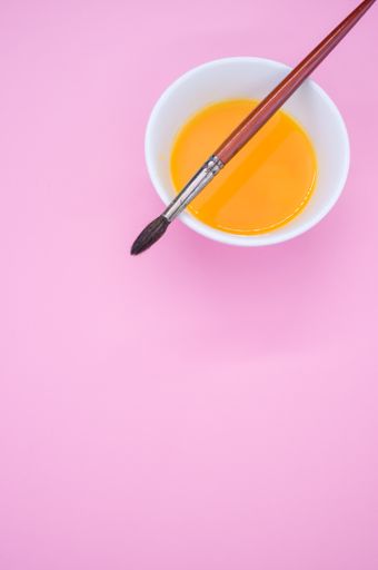 A vertical shot of a paint wash bowl and a paintbrush on pink background with space for your text