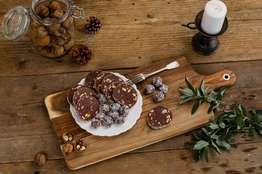 Delicious dried fruit sweets and chocolate sausages on a plate on a wooden board
