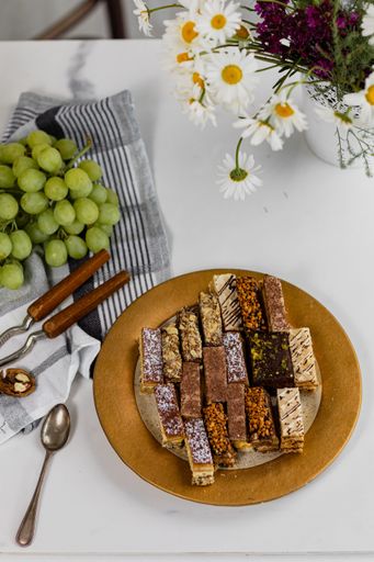 A plate of assorted homemade cakes with grapes and nuts on the table