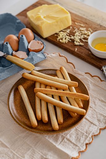 A vertical shot of a plate of fresh breadsticks with some cheese and eggs