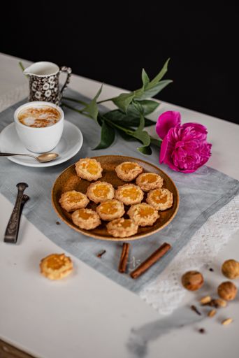 A vertical shot of a plate of biscuits with a cup of coffee and a flowe