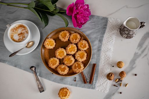 A top view of a plate of biscuits with a cup of coffee and a flower