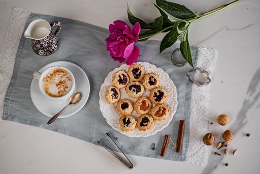 A top view of a plate of biscuits with a cup of coffee and a flower