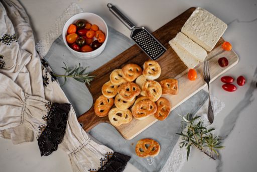 A top view of freshly baked pastry on a wooden cutting board with some cheese and tomatoes