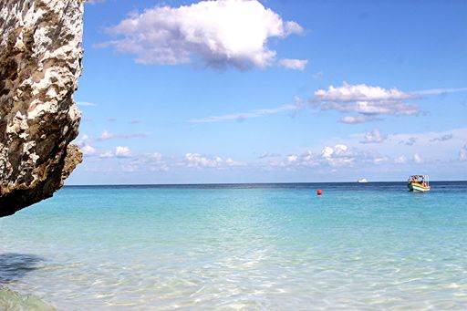 A tranquil seascape, featuring a crystal-clear blue ocean with a small boat floating in Tulum, Mexico