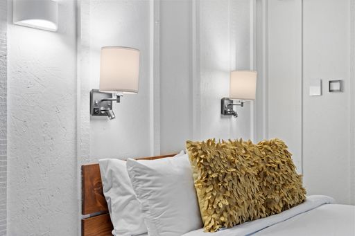 This bedroom has large beds and white walls with white curtains