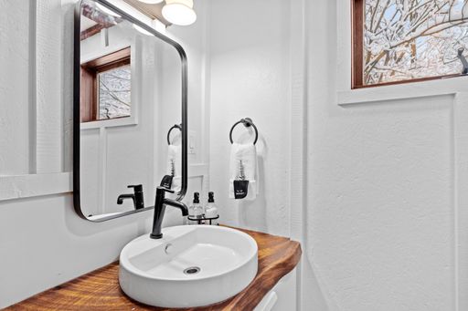 A bathroom wit a wooden shelf below the mirror and a large mirror