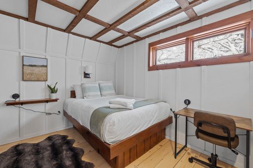 A comfortable white bedroom with a desk, chair, and extensive bed