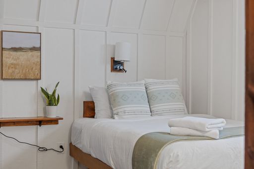 A comfortable white bedroom with a spacious bed and big pillows