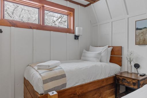 A small comfortable simple bedroom with one bed and white walls