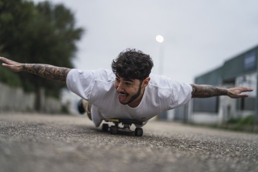 A shallow focus shot of a handsome smiling European guy lying on a skateboard