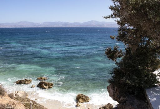 A beautiful shot of a sea with mountains in the distance under a blue sky in island of Paros, Greece