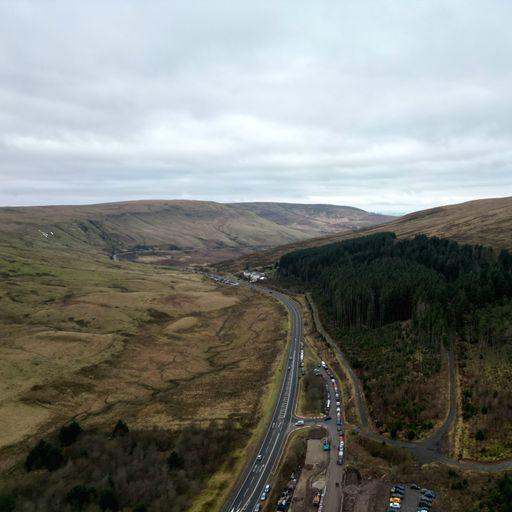 An aerial view of a winding road cutting through a mountain range in the Brecon Beacons, Wales, UK