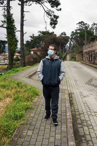A vertical shot of a European tourist in glasses and facial mask walking down the street - new normal concept