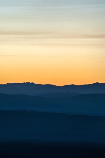 A vertical shot of orange toned vibrant sunset over mountains