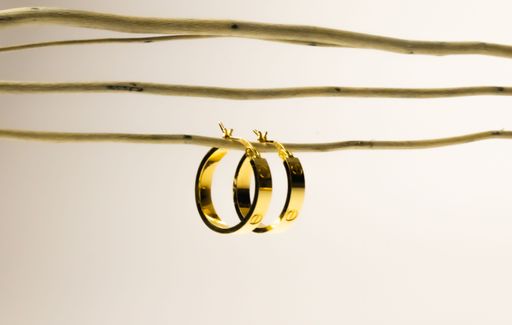 The golden hoop earrings hanging from a wire on the white background