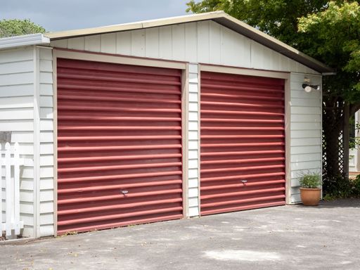 red doors on white building in backyard with trees in the background