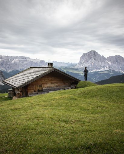 A beautiful shot of a wooden house and a person in Puez-Geisler Nature Park in Miscì, Italy