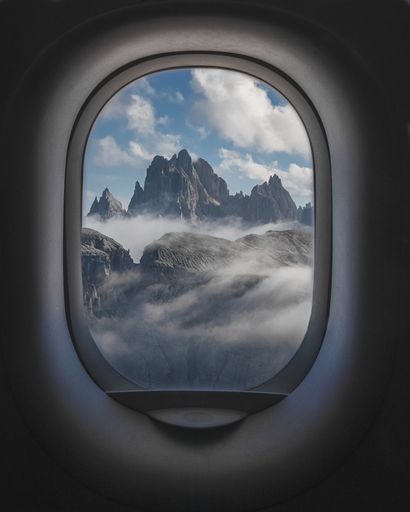 A beautiful shot of mountains and a cloudy sky from the inside of plane windows