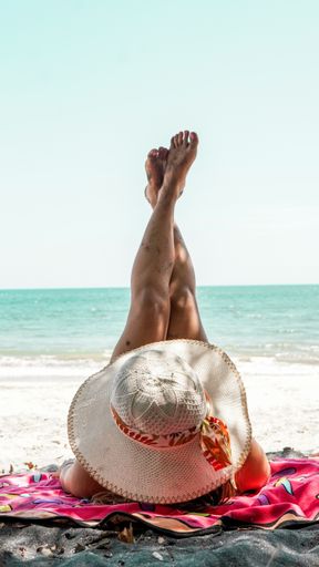 A young Latina woman showing her legs while lying on the beach