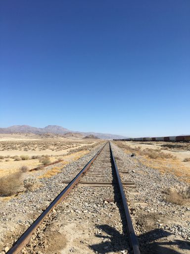 A vertical shot of a train track stretching through a desert landscape