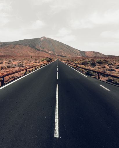 A vertical high angle shot of a highway surrounded by hills under the grey sky