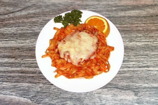 A high angle shot of pasta with tomato sauce with a delicious lasagna at the top