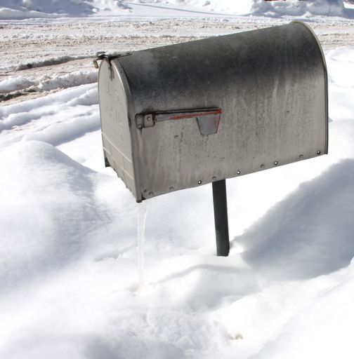An overhead shot of a silver mailbox with snow in the surface during winter