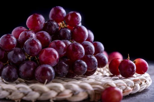 A closeup shot of red grapes on a round board on a gray surface