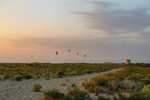 A breathtaking view of Agios Ioannis Beach in Lefkada island with old windmill and kites in the sky at sunset