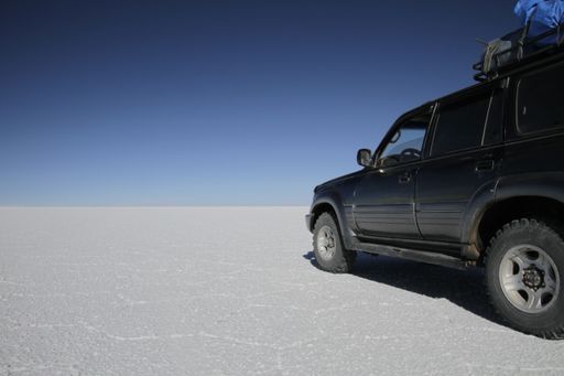 A car on an empty snowy field under a clear blue sky