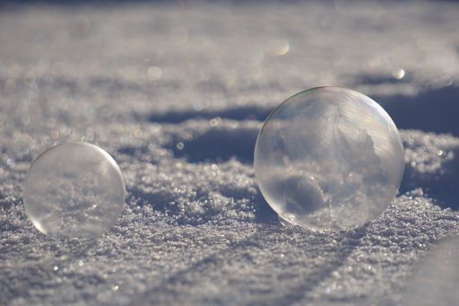 A closeup shot of reflective soap bubbles on the snow under the sunlight