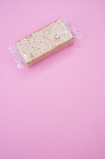 A vertical closeup shot of crackers in a plastic bag isolated on a pink background
