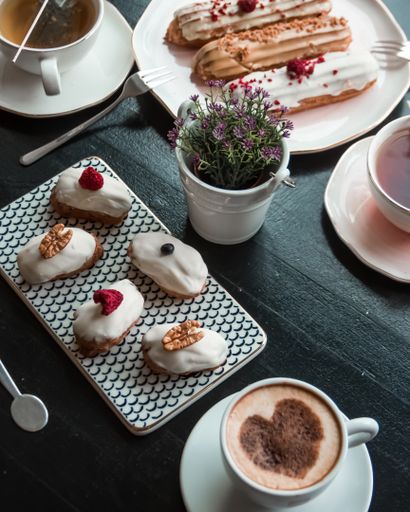 A vertical shot of French eclairs with white chocolate and a cup of coffee