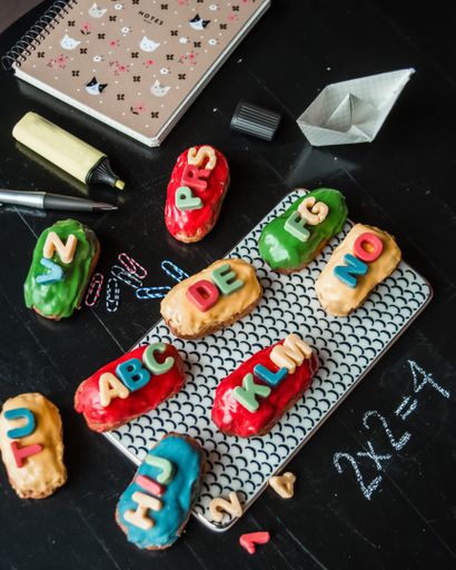 A vertical shot of colorful eclairs with letters next to notebook and planner  back to school concept